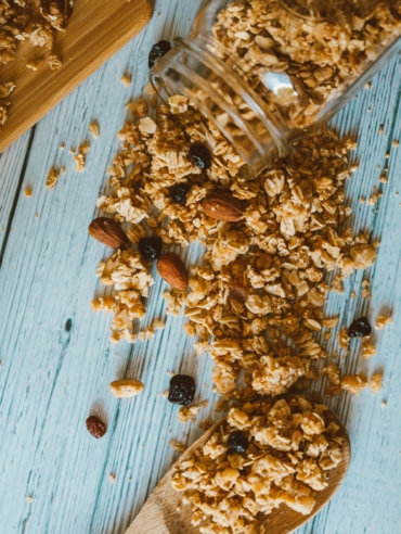 Close-up of spilled granola with almonds and berries on a wooden surface, perfect for breakfast themes.