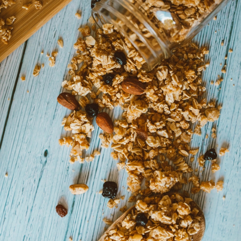 Close-up of spilled granola with almonds and berries on a wooden surface, perfect for breakfast themes.